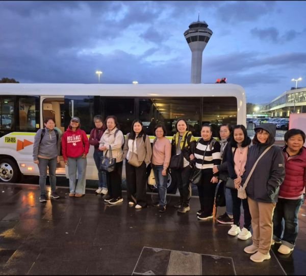 Tour group waiting beside a minibus at the airport in the evening